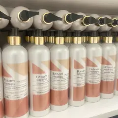 Rząd białych butelek z dozownikiem, każda z etykietą "Balsam łagodzący po depilacji laserowej".