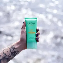 Dłoń z tatuażem trzyma tubkę kremu z filtrem SPF 50. To sposób, jak chronić skórę przed słońcem.